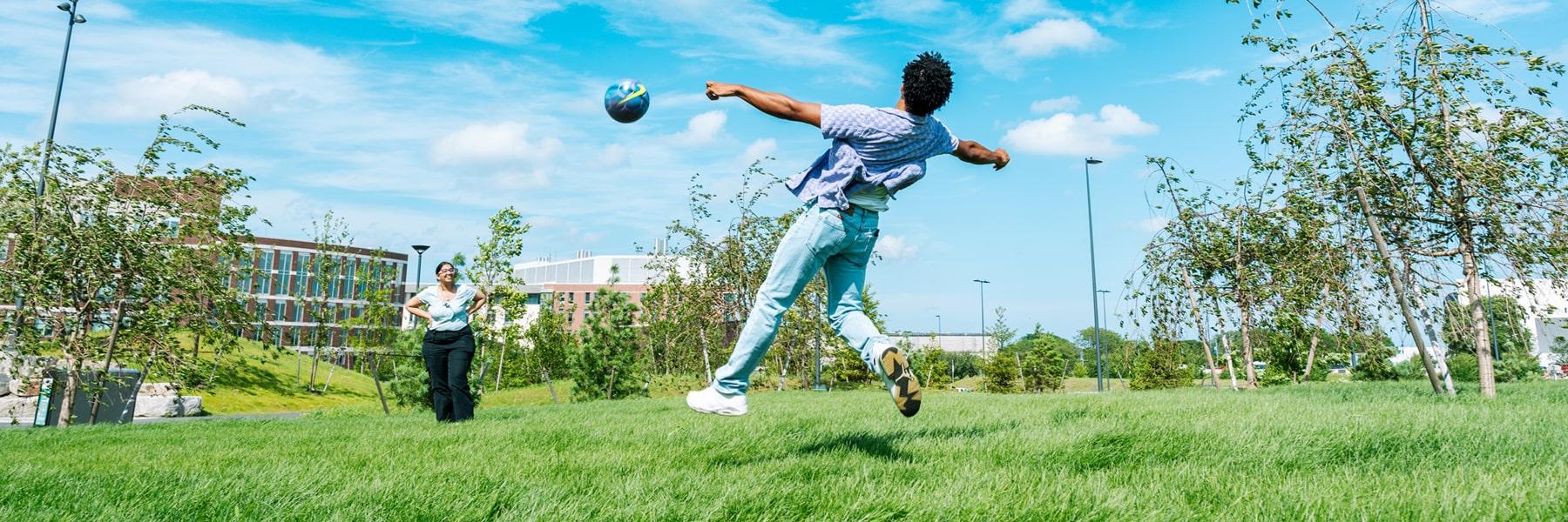 student plays with soccer ball on quad